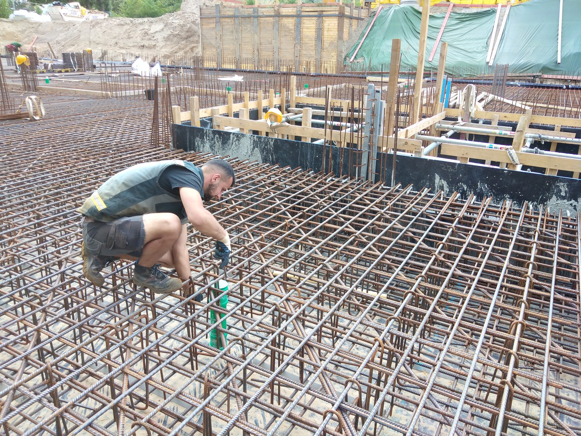 Bauarbeiter legt grüne Kapsel in Bodenplattengitter